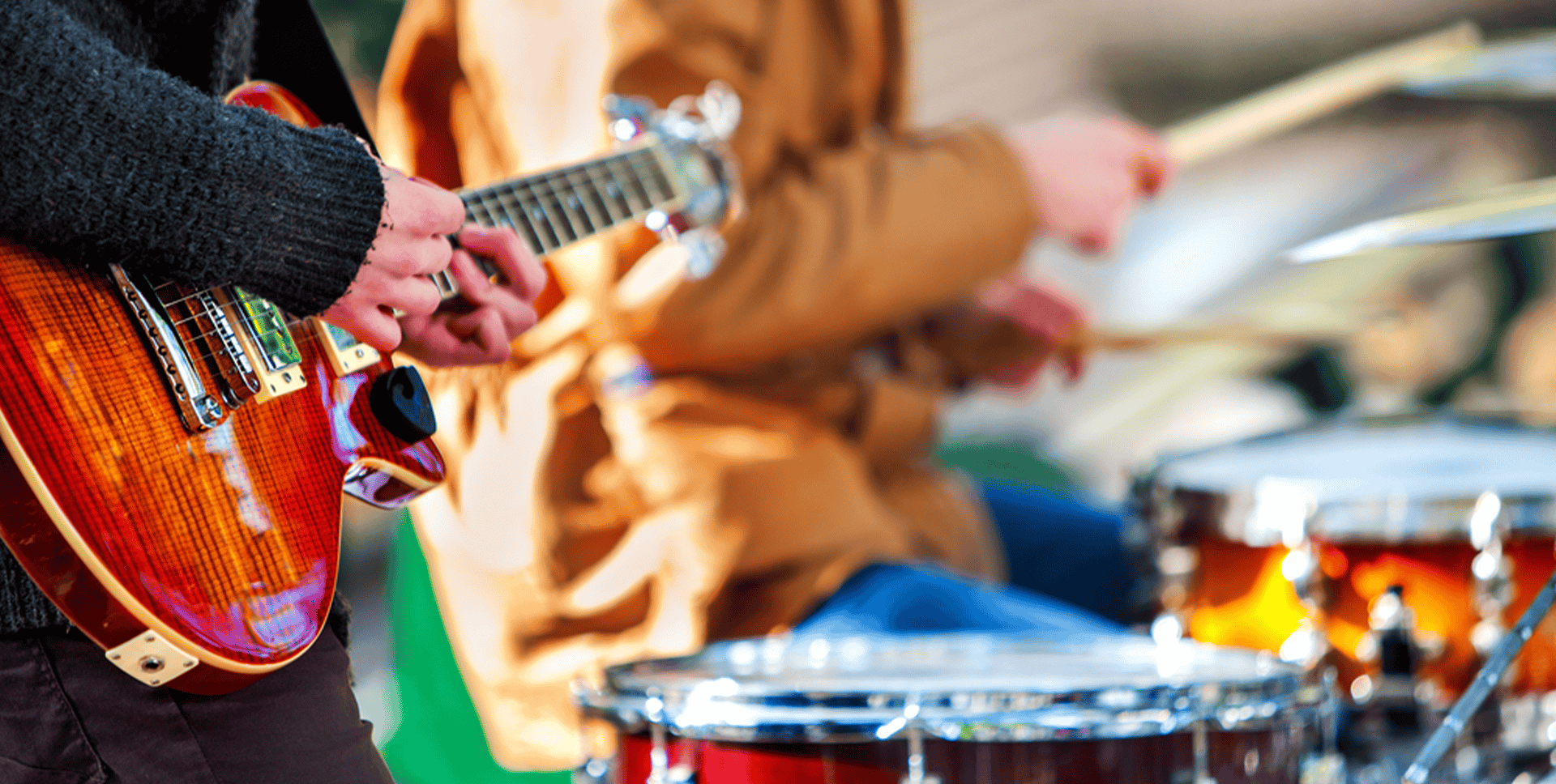Hands playing of guitar next to drums
